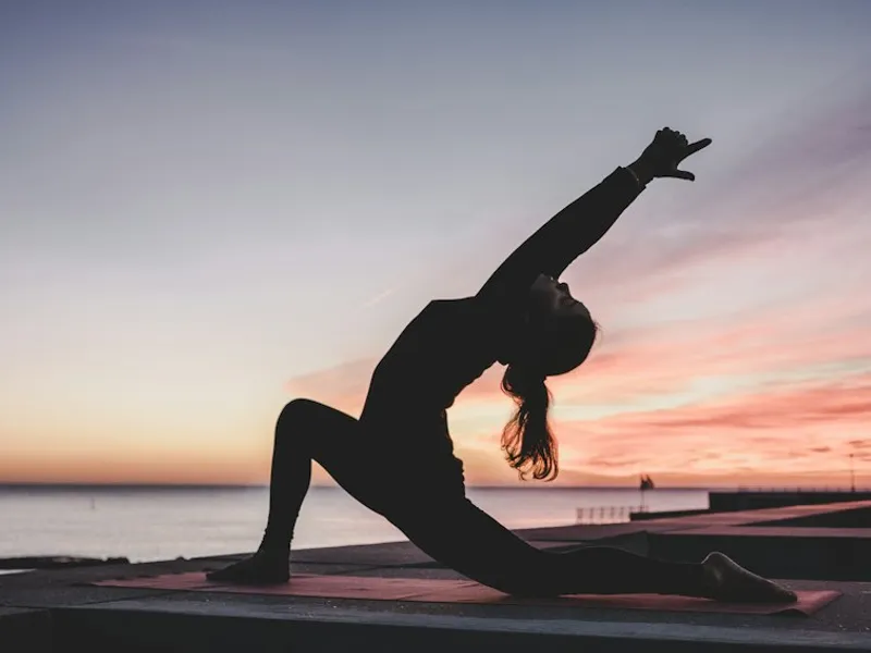 Woman holding a bowl of whole grains and vegetables after yoga