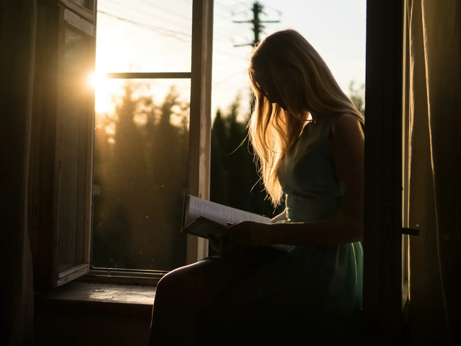 Mujer leyendo junto a una ventana a contraluz