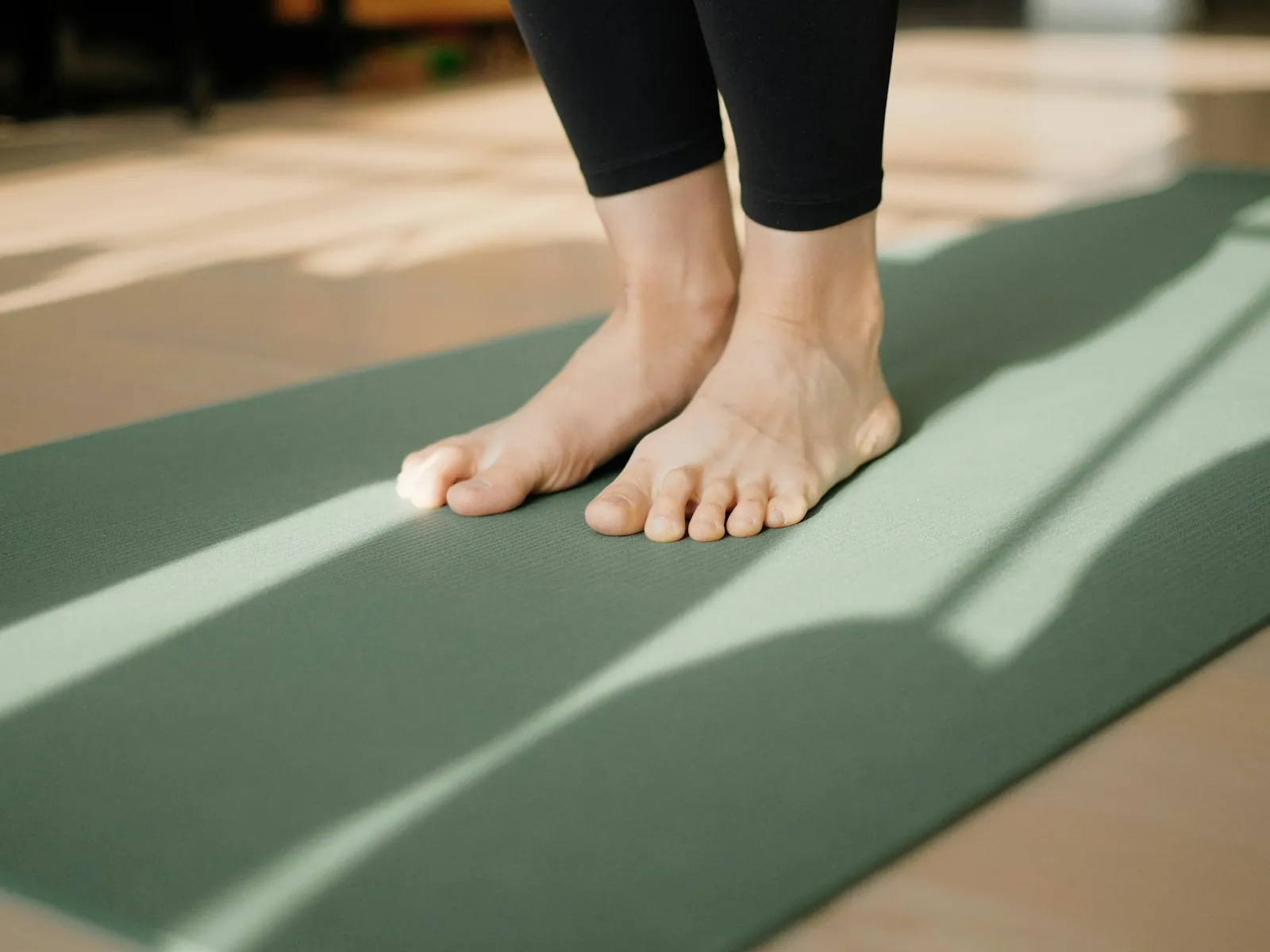 Pies descalzos sobre una esterilla de yoga con luz de sol