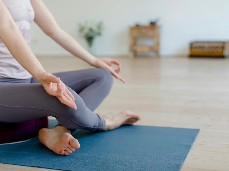 Practitioner sitting in lotus pose on a blue mat